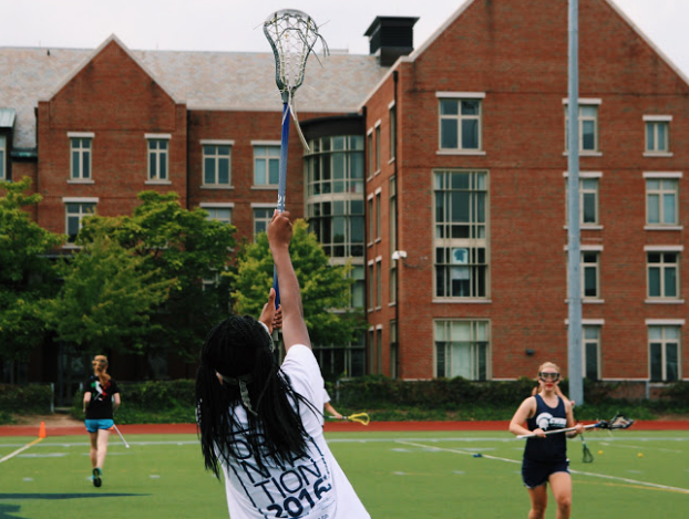A participant of the lacrosse clinic stretches to catch a pass during offensive drills.
