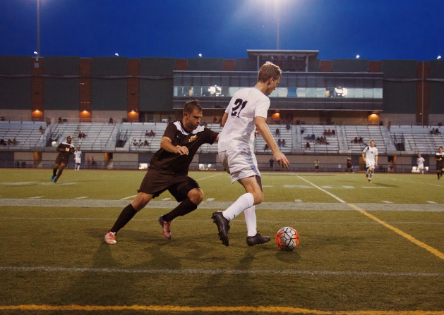 Trying to keep the ball away from a close defender, midfielder Christian Lytle passes the ball to a teammate.