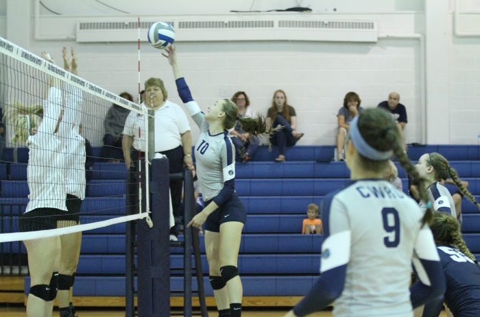 Karley King looks on as Haley Sims reaches for the ball, trying to bury a kill past two defenders.
