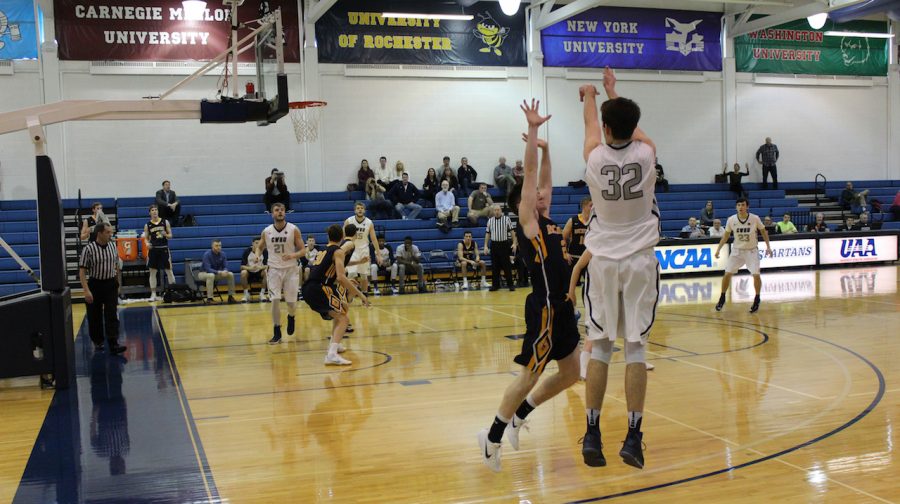 Connor Nally shoots a three-pointer with a hand in his face.
