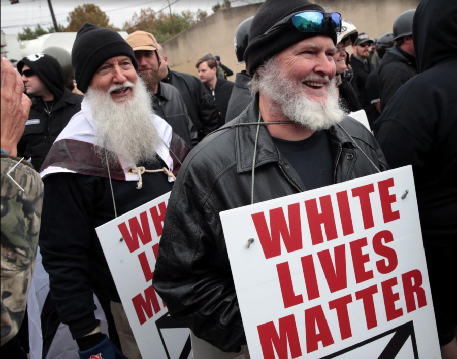 Protesters hold up signs displaying the White Lives Matter slogan.