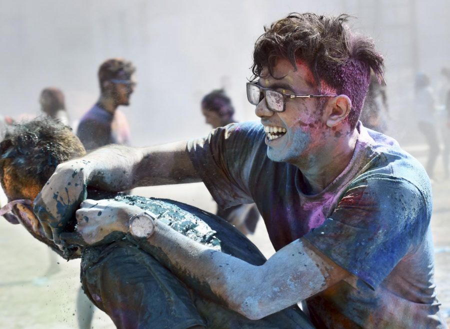 Two participants of Holi enjoy the warm day while covered in pigments of color.
