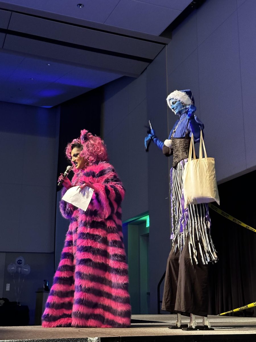 First-year student and costume contest winner Atlas Rivera is congratulated by drag queen performers at oSTEM's HalloQueen Drag Show.